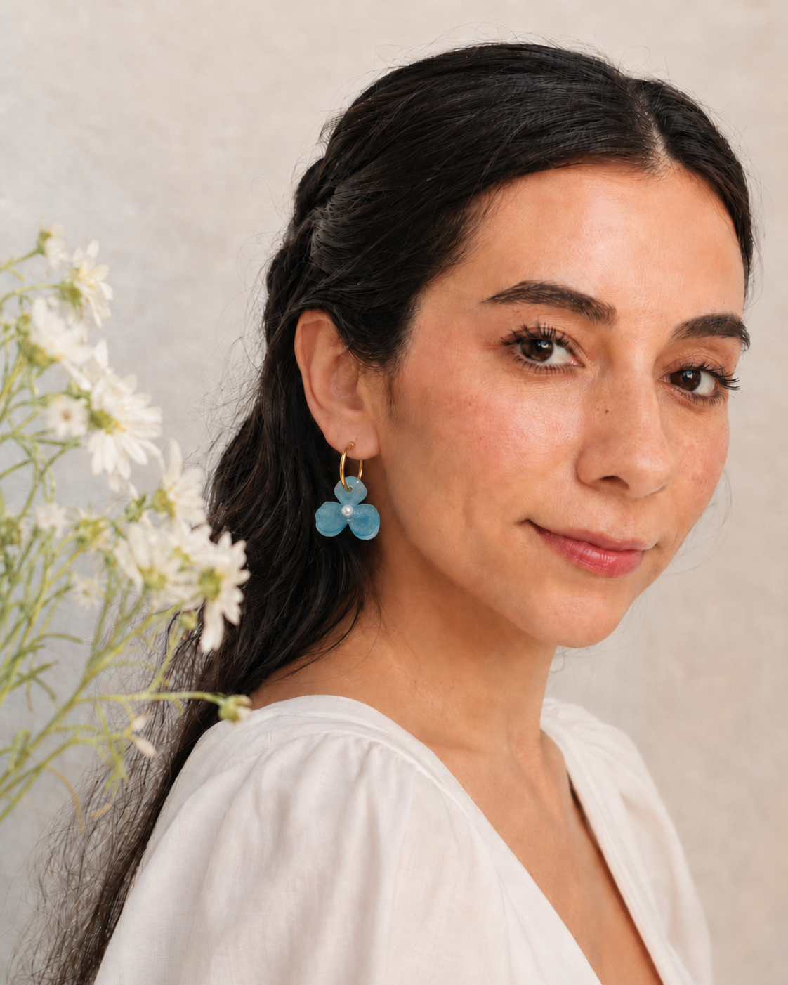 Modelo usando arete Aura Celeste con flor azul de resina y aro dorado
