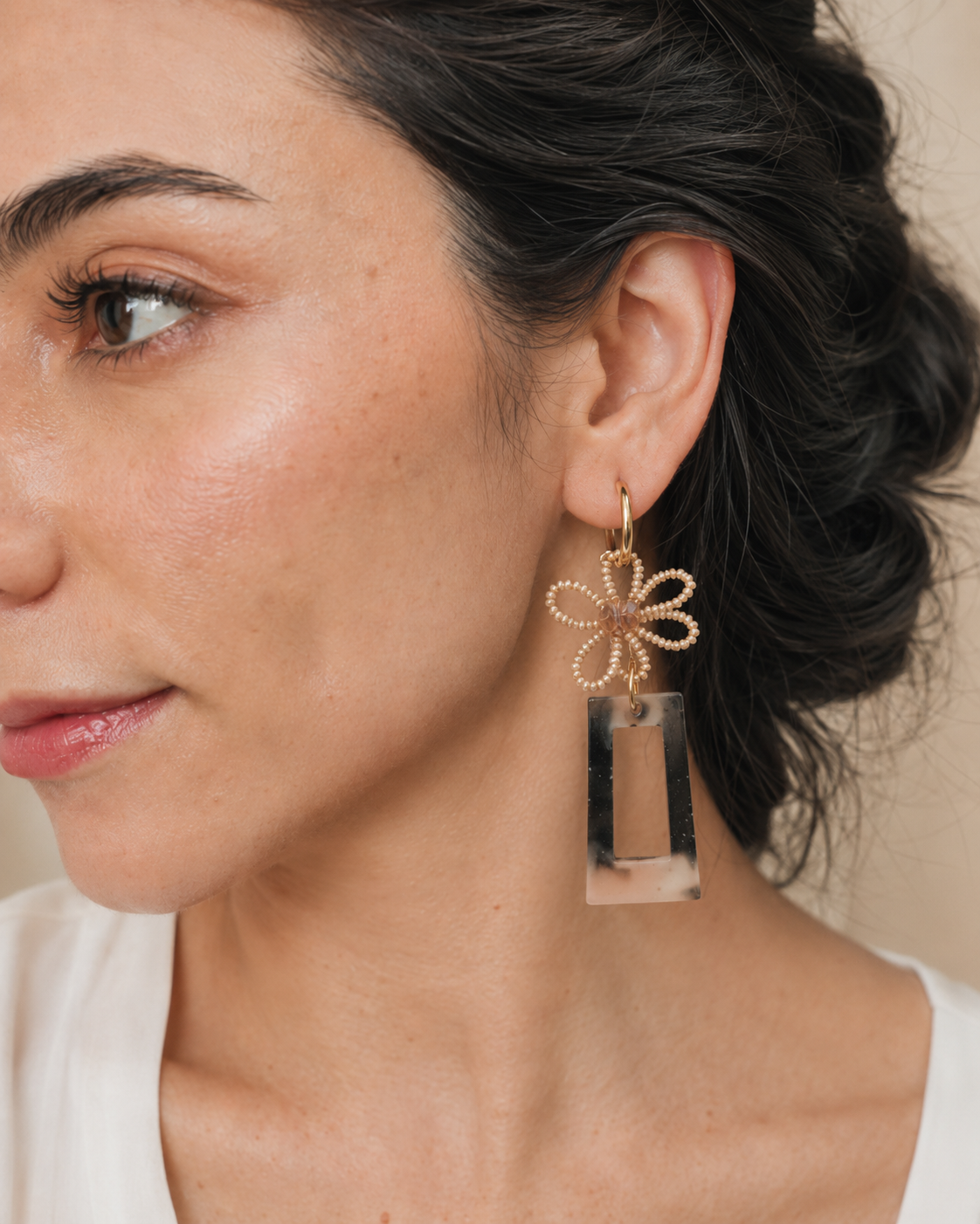 Detalle en modelo de arete artesanal largo con flor de mostacillas y pieza geométrica de resina