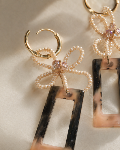 Detalle cercano de flor hecha a mano con mostacillas y murano en arete largo de resina
