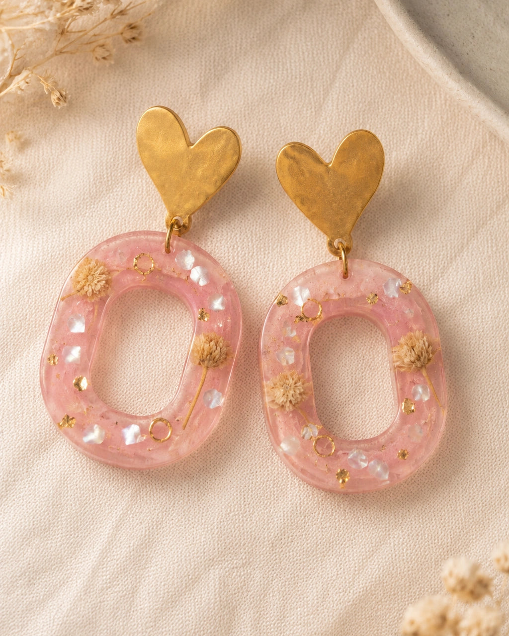 Macro de resina rosa, flores secas y detalles dorados de los aretes Dulce Corazón