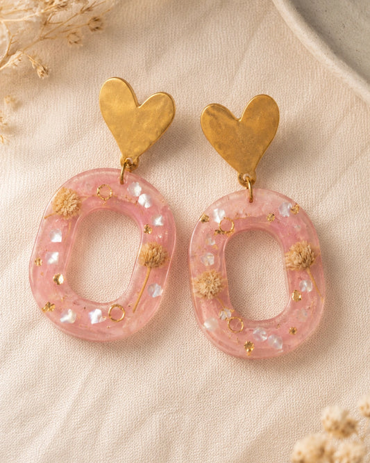 Macro de resina rosa, flores secas y detalles dorados de los aretes Dulce Corazón