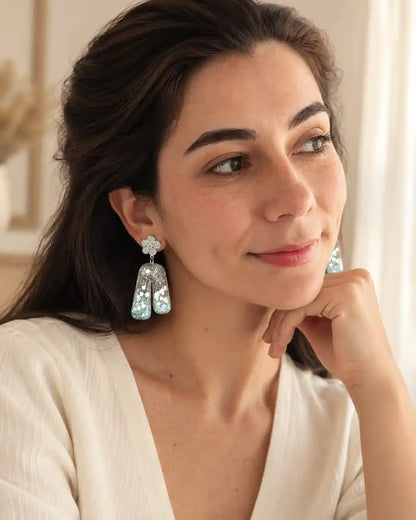 Aurora Clara, aretes de flor plateada y arco translúcido, ángulo complementario en modelo