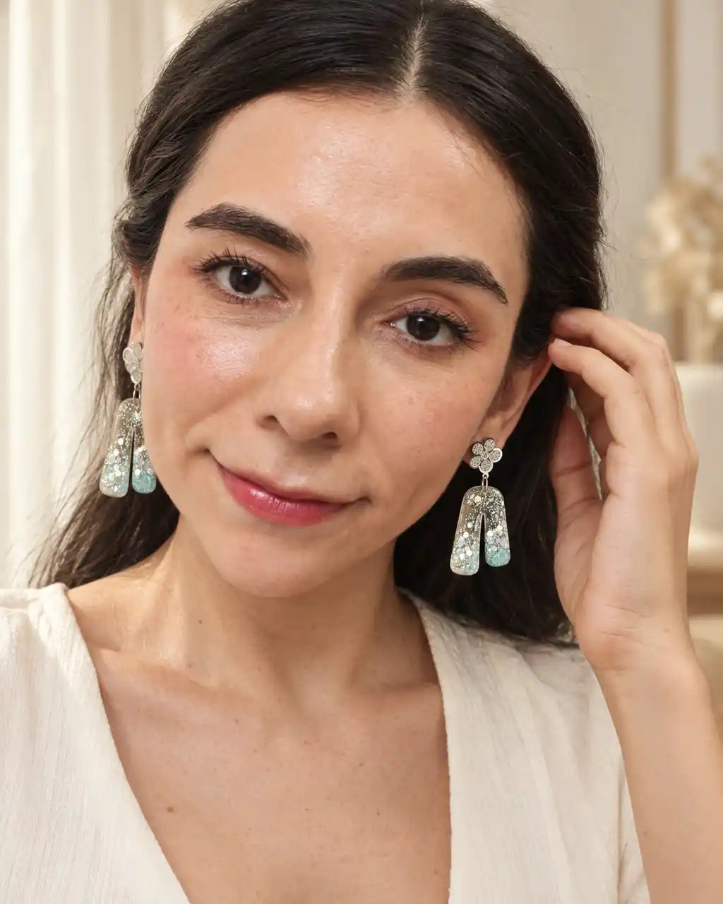 Aurora Clara, aretes de flor plateada y arco translúcido, gesto en modelo