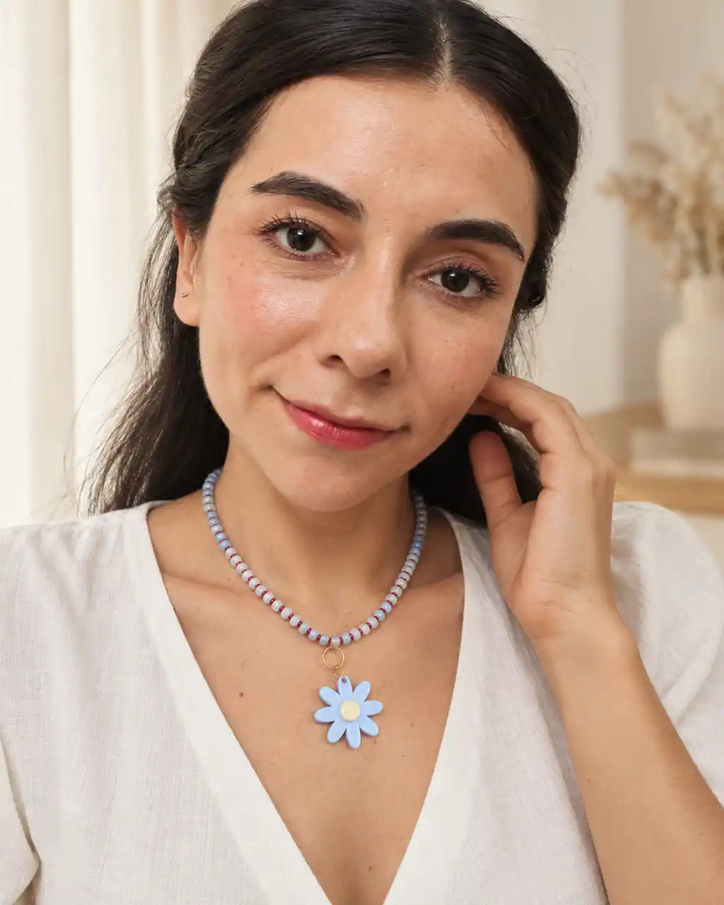 Margarita Celeste, collar corto de cuentas azules y flor azul, gesto en modelo