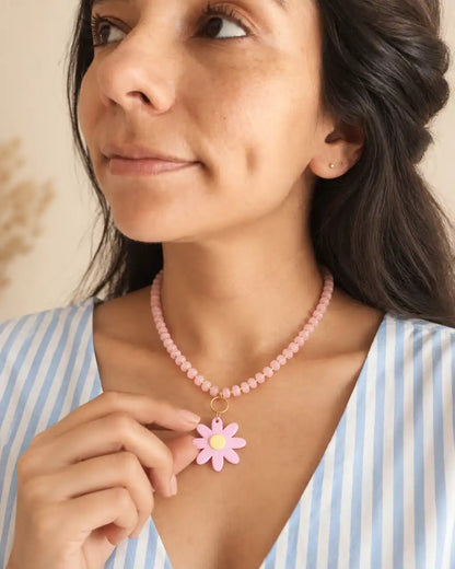 Rosa Silvestre, collar rosado con margarita de centro amarillo, gesto en modelo