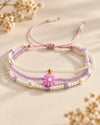 Jardín Violeta – Pulsera multihilo con flor rosada