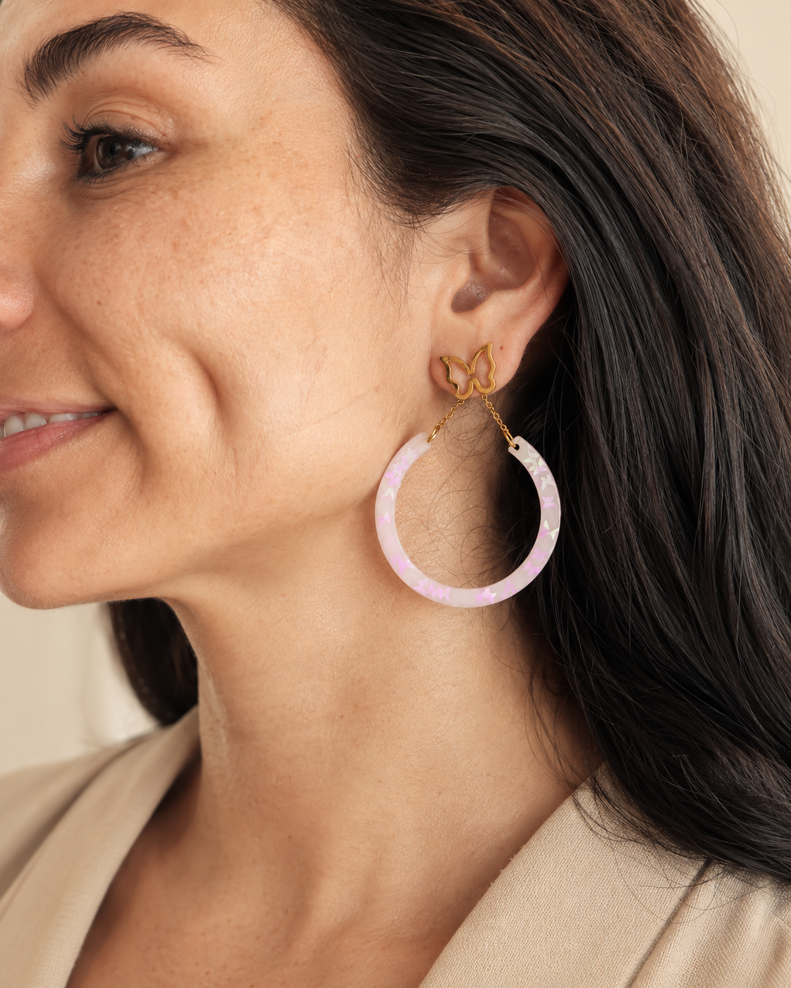 Modelo usando arete de mariposa con aro rosado iridiscente
